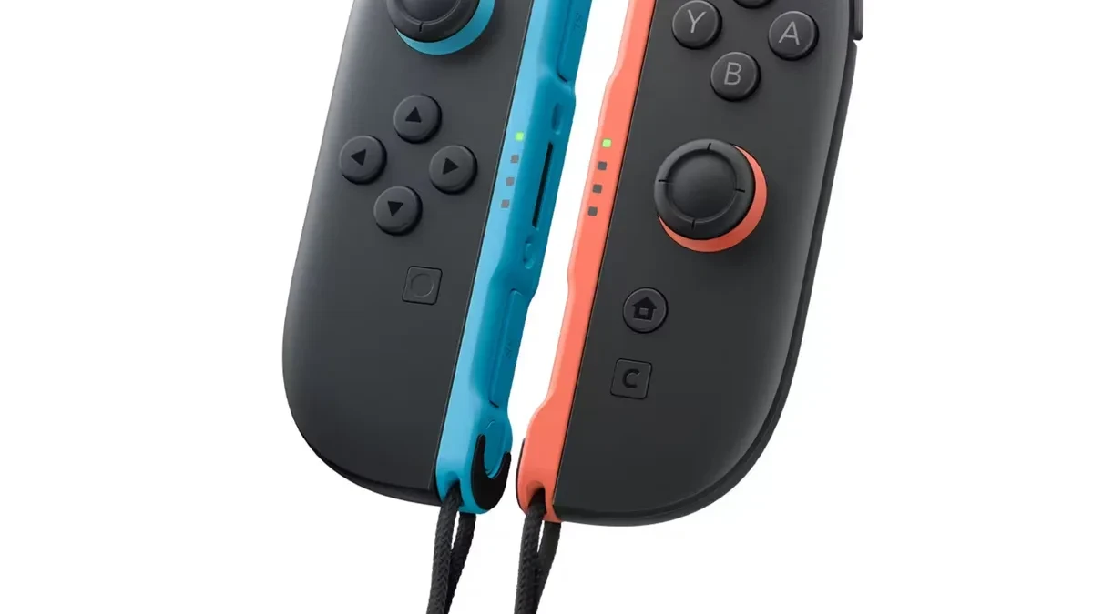 A technician performing a teardown on a pair of Nintendo Joy-Con 2 controllers on a workspace desk.