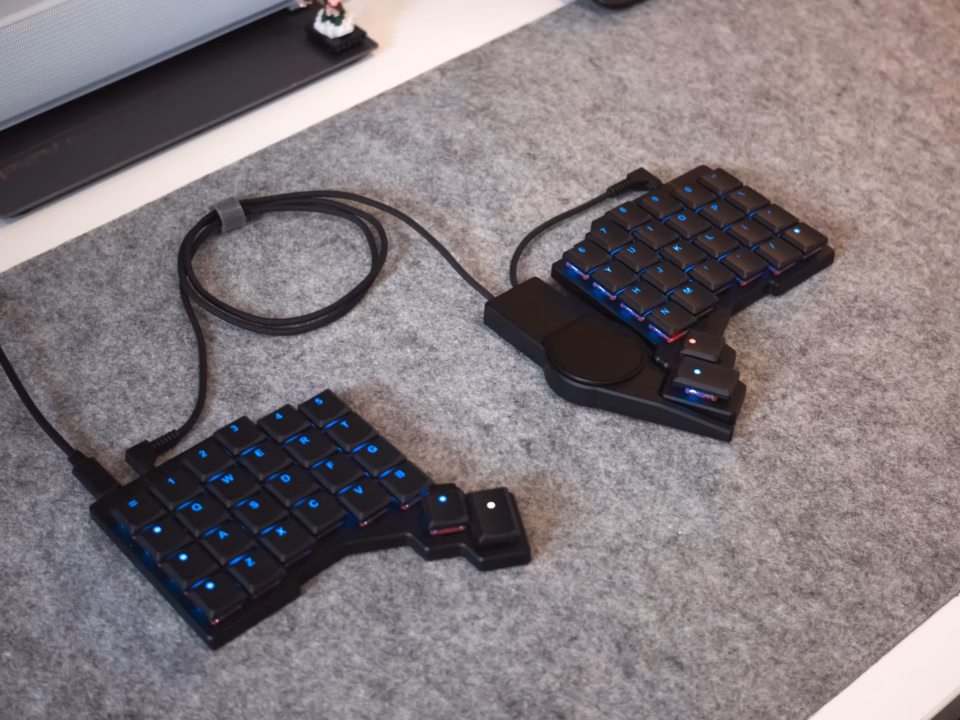 ZSA Voyager mechanical keyboard with the Navigator Trackpad attached showing multi-touch gestures